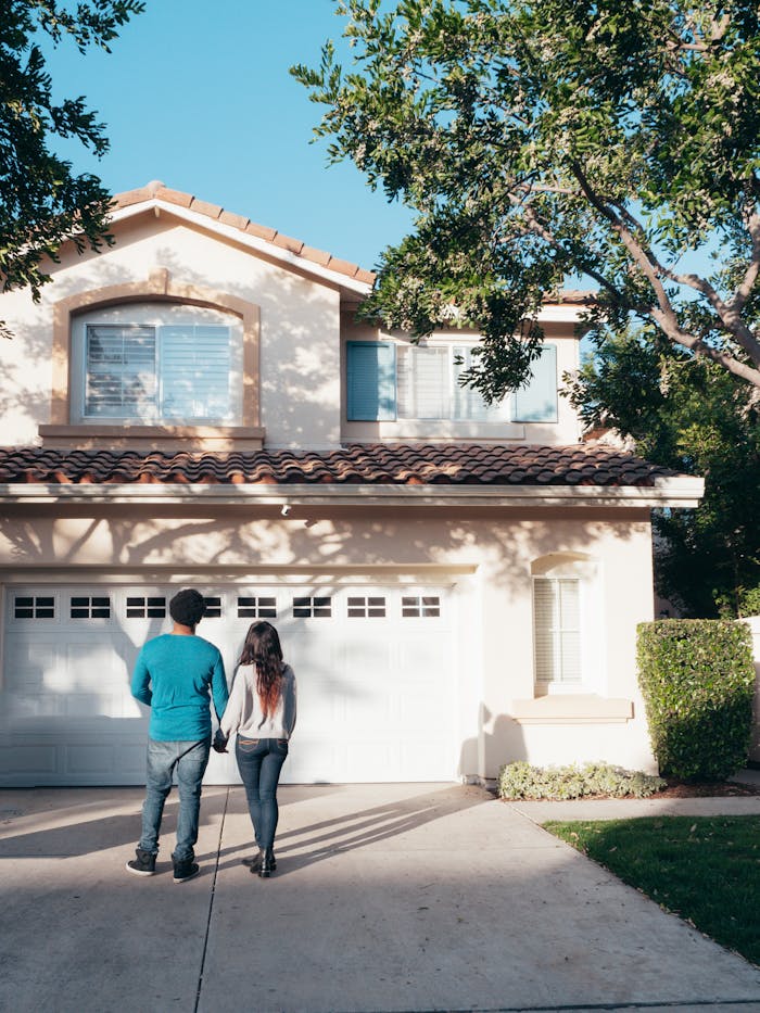 A couple stands hand in hand, admiring their new house and life ahead.